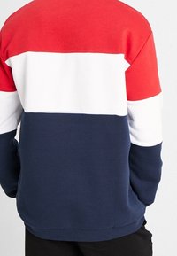 Felpa girocollo con blocchi di colore orizzontali in rosso, bianco e blu navy. Realizzata in tessuto morbido con polsini e orlo a costine.