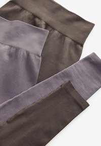 Leggings i mørkebrun og afdæmpet lilla. Har ribbet tekstur og brede taljebånd. Stabelt stof viser kontrasterende farver og materialer.
