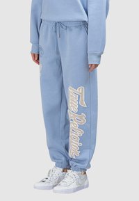 Hellblaue Sweatpants aus Baumwolle mit Kordelzug in der Taille, gerippten Bündchen und weißem "True Religion"-Schriftzug an der Seite.