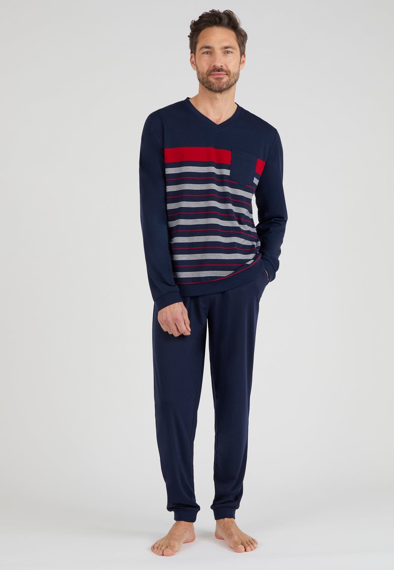 Langsleeve marineblauwe V-hals top met rode en grijze horizontale strepen, gecombineerd met bijpassende marineblauwe broek. Zachte stof en een relaxte pasvorm.