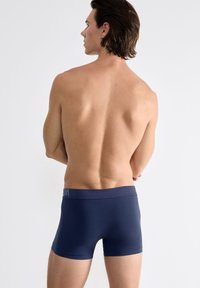 Boxer shorts azul marino fabricados con tejido elástico, que cuentan con una amplia cintura elástica con detalles del logo en la parte frontal.
