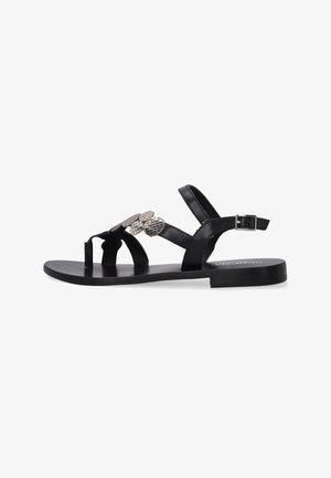 Sort lædersandal med flad sål, flere stropper og dekorative metal detaljer på overdelen. Har en justerbar ankelspænde.