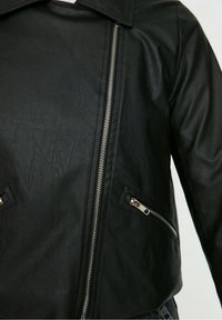 Zwarte leren jas met een gekartelde kraag, ritssluiting aan de voorkant en zijzakken. Heeft een gestructureerde afwerking en zilveren hardware accenten.