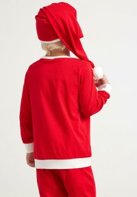 Czerwony komplet piżam bawełnianych z białymi wykończeniami, z długimi rękawami i stożkowym kapturkiem z pomponem na czubku. Prosty design i faktura.
