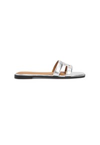 Sølvmetallic slide sandal med to brede stropper, flad sål og en glat tekstur. Har en sort bund og en tan fodseng.