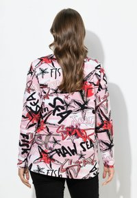 Langarmtop met een roze en zwart grafisch patroon van sterren en gestileerde tekst, gemaakt van lichtgewicht stof met een gladde textuur.