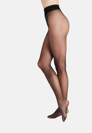 Piernas con medias negras transparentes con pretina reforzada, vistas de lado contra un fondo claro y liso.