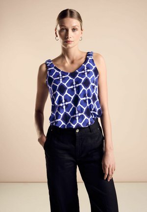 Blau gemusterter Tanktop mit geometrischem Design, kombiniert mit schwarzen, weit geschnittenen Hosen. Der Stoff hat eine glatte Textur und eine lässige Passform.