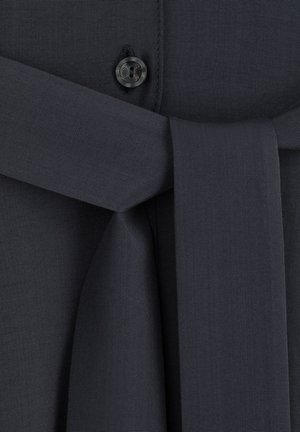 Ciemnoszara tkanina o gładkiej strukturze, z zapięciem na guzik i jeżyną w talii. Prosty wzór z czystymi liniami i minimalną ilością hardware'u.