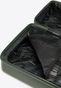 Otevřený zelený tvrdý kufr s černým vzorovaným vnitřním potahem, síťovanou kapsou se zipem a látkovým rozdělujícím klapkou uvnitř.