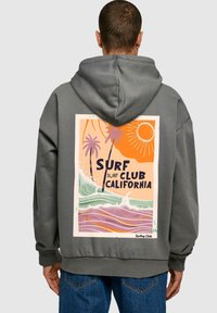 Felpa grigia con stampa colorata sul retro che presenta palme, onde, sole e la scritta: "SURF CLUB CALIFORNIA" in caratteri in grassetto. Materiale in cotone.