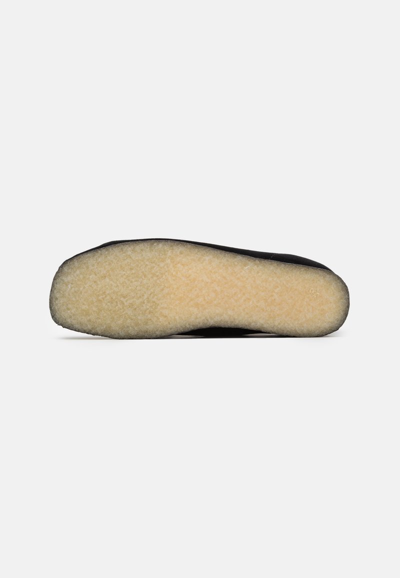 Zwarte schoenzool met een gladde zwarte rand en een zachte beige, gestructureerde middenstuk. Ontworpen voor comfort met een minimalistische vorm.