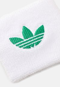 Pulseira branca de algodão com um logótipo verde bordado em forma de folha com três folhas, acompanhado de três riscas horizontais em baixo. Superfície suave e texturada.