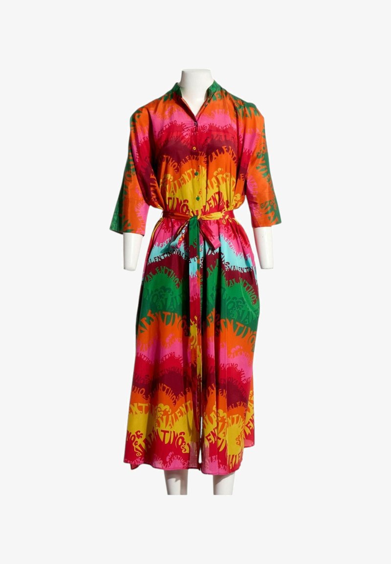 Robe midi boutonnée colorée avec manches longues et ceinture à la taille, présentant un motif vif avec texte et formes abstraites.