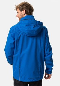 Wasserabweisende blaue Jacke mit Kapuze, elastischen Bündchen, einem Kordelzugsaum und einem Logo im unteren Rückenbereich. Glattes, leichtes Material.