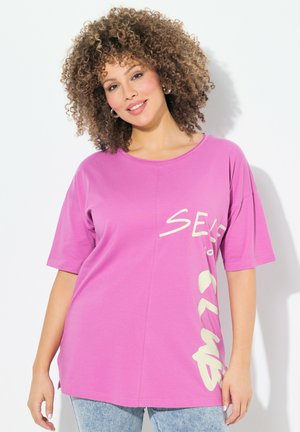 Roze T-shirt met een oversized pasvorm, korte mouwen en een grafische tekstontwerp in licht beige aan de voorkant. Zacht materiaal met een gladde textuur.