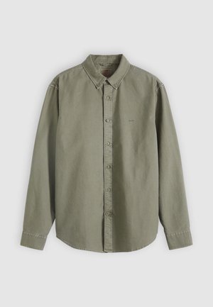 Παντελόνι κουμπωτό σε ανοιχτό πράσινο χρώμα, κατασκευασμένο από απαλό βαμβάκι, με κλασικό γιακά, μακριά μανίκια και κουμπιά στο μπροστινό μέρος. Διακριτική επωνυμία στο στήθος.