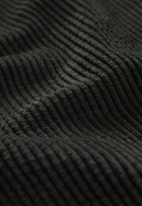 Zwart ribstof met verhoogde verticale strepen, die een zachte textuur en een gelijkmatig patroon over het oppervlak toont.
