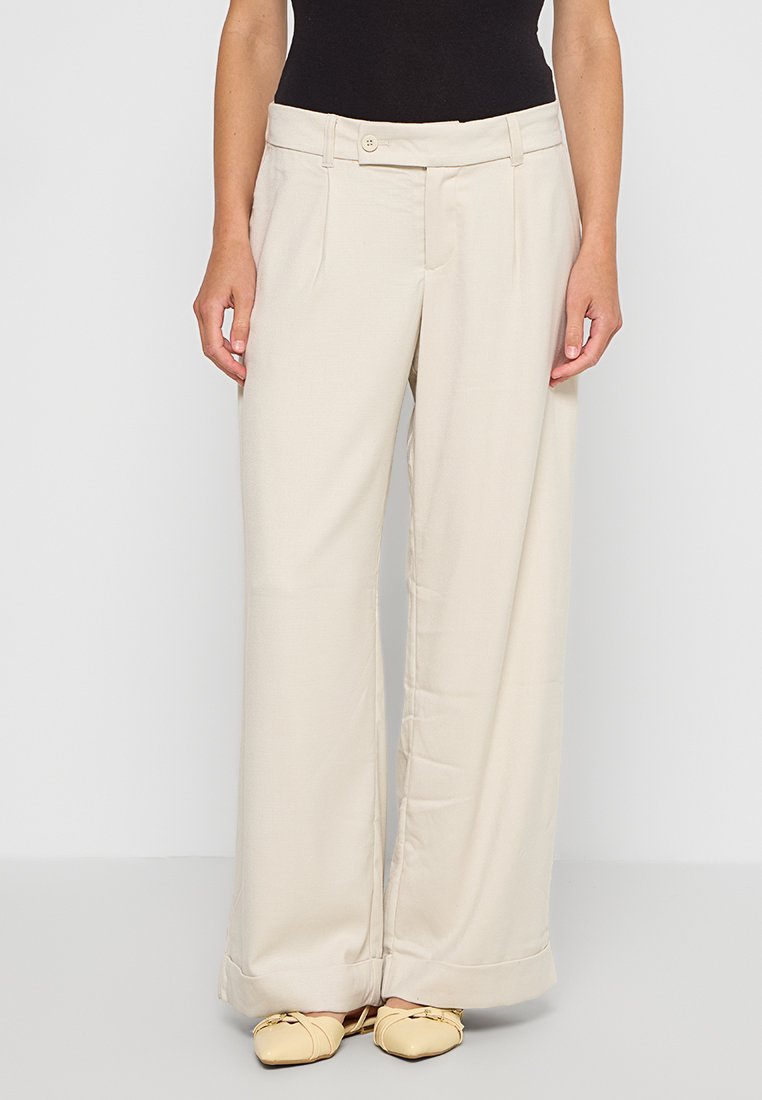 Beige weite Hosen aus einem glatten, leichten Stoff. Ausgestattet mit einem Knopfverschluss, zwei vorderen Falten und einem subtilen Glanz.