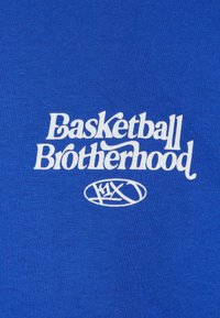 Kara zila auduma, kuram ir balts teksts "Basketball Brotherhood" ar stilizētu logotipu zem tā, izceļot vienmērīgu tekstūru.