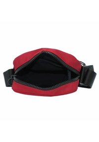 Borsa a tracolla rossa in tessuto con apertura a cerniera, interni neri e tracolla nera regolabile. Presenta una texture liscia e una forma arrotondata.