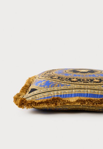 Kvadratna blazina z modrim in zlatim vzorčastim materialom z zapletenimi dizajni, zaključena z teksturiranim zlatim resicami.