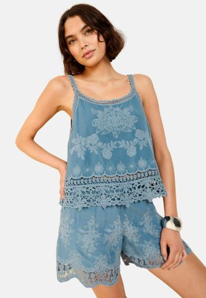 Blauwe geborduurde top met kantafwerking, gecombineerd met bijpassende shorts. Bloemenpatronen en delicate details verbeteren de lichte stof.