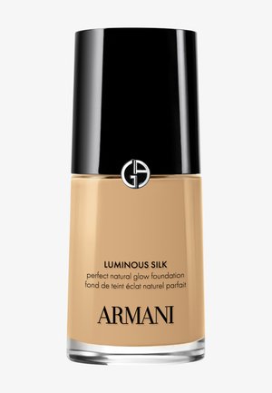 Luminous Silk foundation in een doorzichtig glazen flesje met een zwarte dop. Beige kleur met zwarte en zilveren tekst. Heeft het Giorgio Armani-logo.