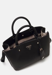 Sac à main en cuir noir texturé avec deux anses, ferrures dorées, étiquette attachée, doublure intérieure visible beige, marqué d'un logo métallique triangulaire.