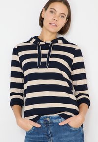 Marineblauer und beiger gestreifter Hoodie mit Kordelzug, langen Ärmeln und lockerer Passform. Kombiniert mit Denim, mit abgerundetem Saum.