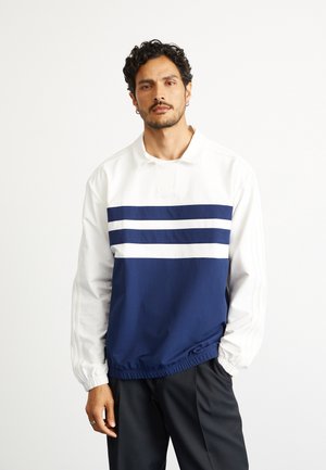 Marineblå og hvid pullover med høj krave, prydet med tre vandrette striber, elastiske manchetter og en samlet detalje forneden. Blød, glat tekstur.