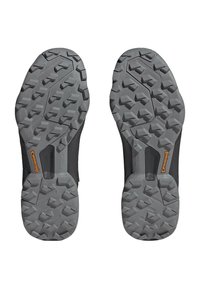 Czarne buty sportowe z szarymi gumowymi podeszwami; bieżnik posiada wielokierunkowe wypustki dla lepszej przyczepności, zawiera widoczne logo Continental.