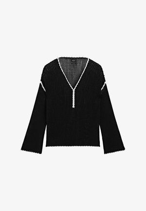 Pull en maille noir avec un col en V, featuring un passepoil blanc le long de l'encolure et des manches. Il a des manches larges et courtes et une finition texturée.