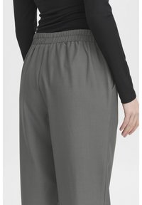 Pantalons légers gris avec une taille élastique, comportant des poches latérales et un tissu lisse et texturé.