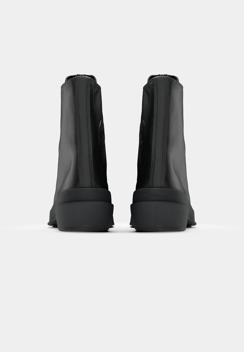 Bottines noires en cuir lisse, avec un talon texturé, un logo discret et une pointe arrondie, conçues avec une esthétique minimaliste.