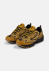 Sneaker gialli e neri con tomaia in suede e mesh, suola testurizzata, ammortizzazione spessa e lacci con motivo, dotati di una linguetta sul tallone.