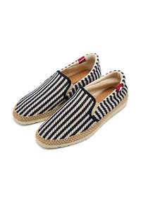 Scarpe slip-on a righe con un pattern blu e crema, parte superiore in tela, bordi in juta e una suola in gomma chiara. Logo di accento sul lato.
