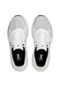 Hvide sportssko med mesh-overdel, fremtrædende snøresystem, sort polstret inderside og logo på tungen og sålen. Cloud-cushioning design.