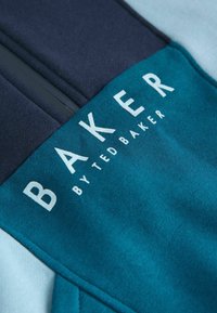 Sudadera en tono azul verdoso y marino con cremallera en el frente. Presenta un destacado logo "BAKER by Ted Baker" en blanco. Tejido suave con una textura lisa.