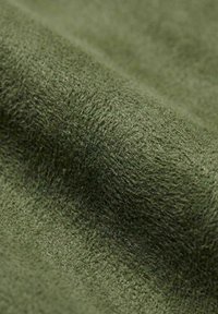 Nærbilde av olivengrønn teksturert stoff som viser strikkemønster og myke fibre.