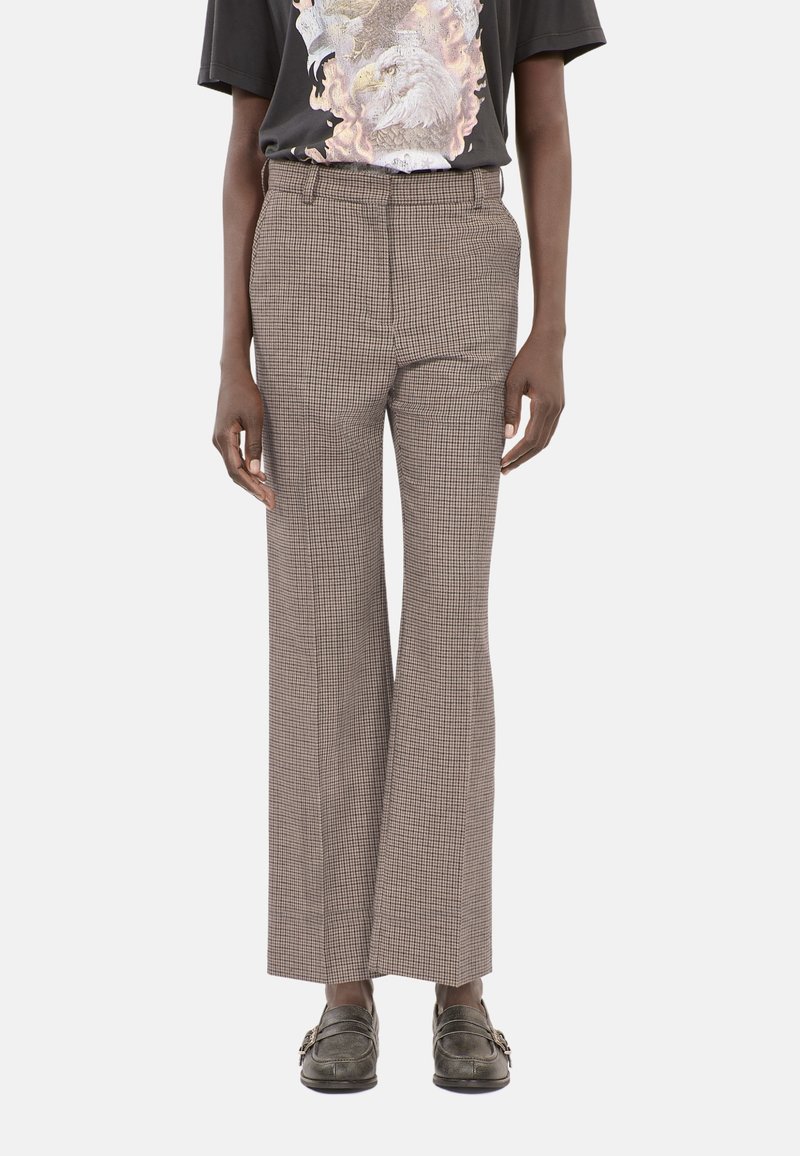 Beige rutig mönstrade byxor med hög midja och vida ben. Tyget verkar strukturerat, i kombination med en svart grafisk t-shirt och grå loafers.