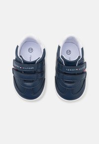 Námořnické modré boty pro batolata vyrobené z umělého materiálu s bílými akcenty. Obsahují suchý zip a logo na boku. Velikost 17.