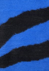 Têxtil felpudo em azul com duas faixas onduladas em preto. A superfície parece macia, com um acabamento ligeiramente texturizado.