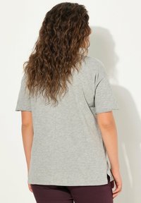 Lichtgrijze T-shirt met korte mouwen, gemaakt van zachte katoen, met een losse pasvorm, zijsplitsen en een eenvoudig ontwerp zonder zichtbare patronen.