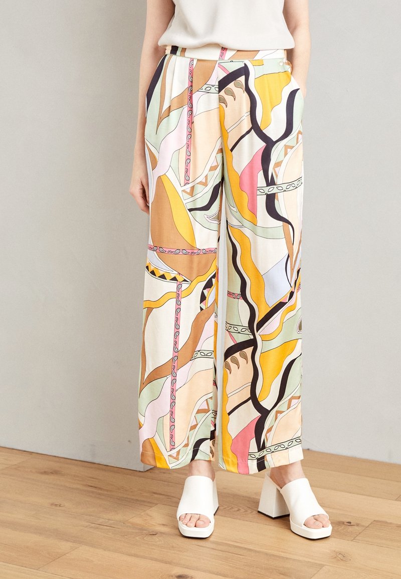 Pantalons à jambe large en tissu léger, avec un motif abstrait coloré comprenant des tourbillons, des lignes et des formes dans des teintes de jaune, rose et vert.