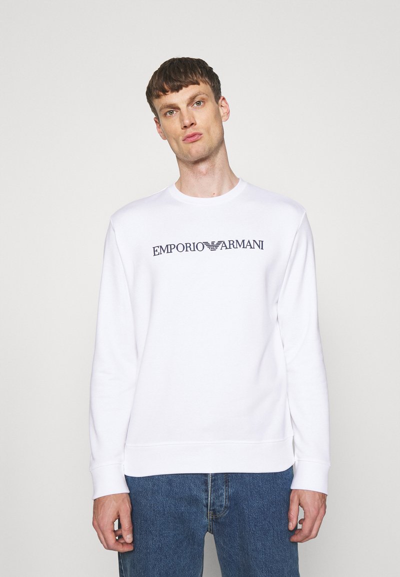 Biela mikina s okrúhlym výstrihom a dlhými rukávmi, na prednej strane s tmavomodrým logom "EMPORIO ARMANI". Bavlnený materiál.