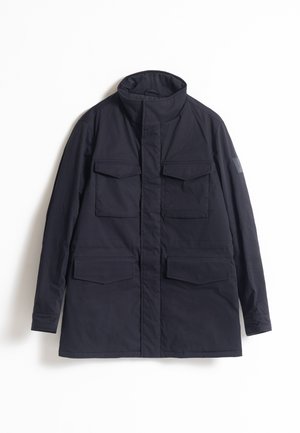 Chaqueta ligera de exterior color azul marino con un alto cuello, cuatro bolsillos frontales y una textura suave. Presenta un parche en el brazo izquierdo.