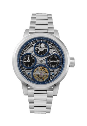 Montre en acier inoxydable avec un cadran squelette bleu et noir, dotée d'un affichage double de l'heure et de rouages décoratifs, maintenue par un bracelet en métal brossé.