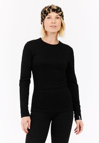 Zwarte langemouwen top met gestructureerde strepen, ronde halslijn en getailleerd ontwerp. Gecombineerd met zwarte leggings met patroon en een panterprint hoofdband.