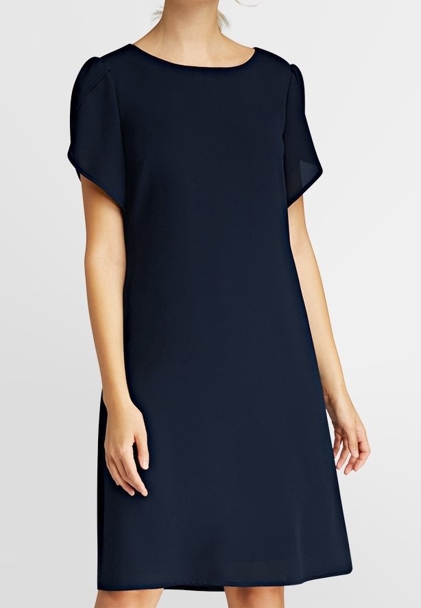 Femme portant une robe noire simple, à manches courtes, longueur genou, avec un col rond sur un fond clair uni.